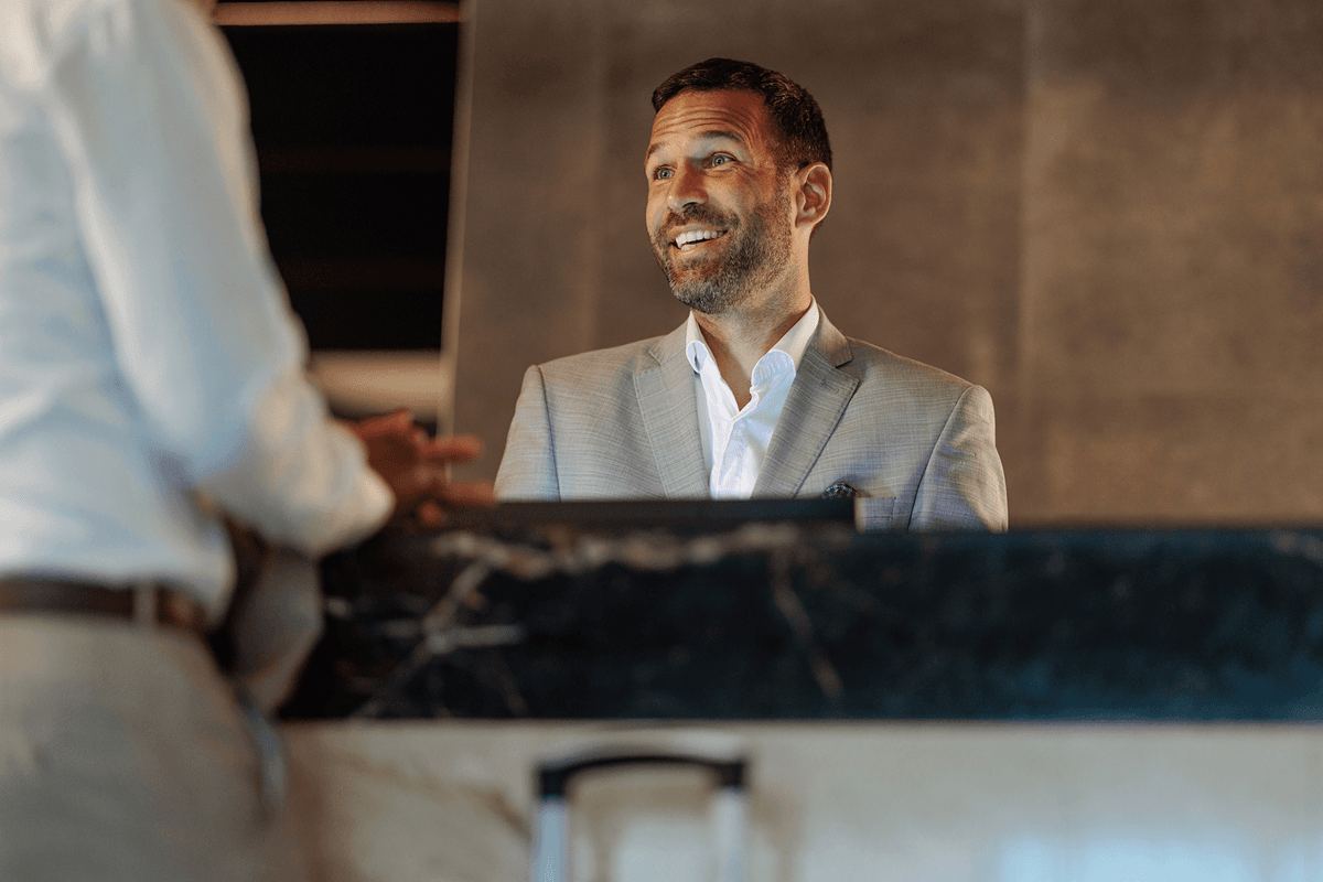 A man in a suit is smiling while talking to another man.